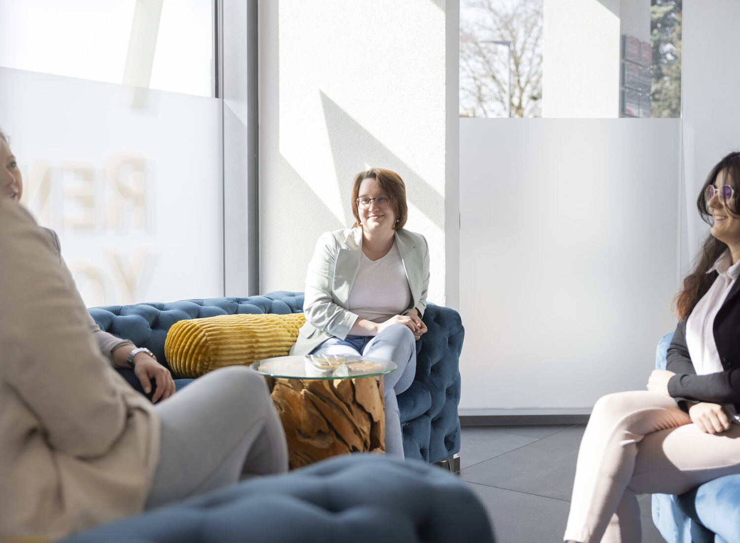 Mehrere Personen sitzen auf Sofas n einem Meeting zusammen