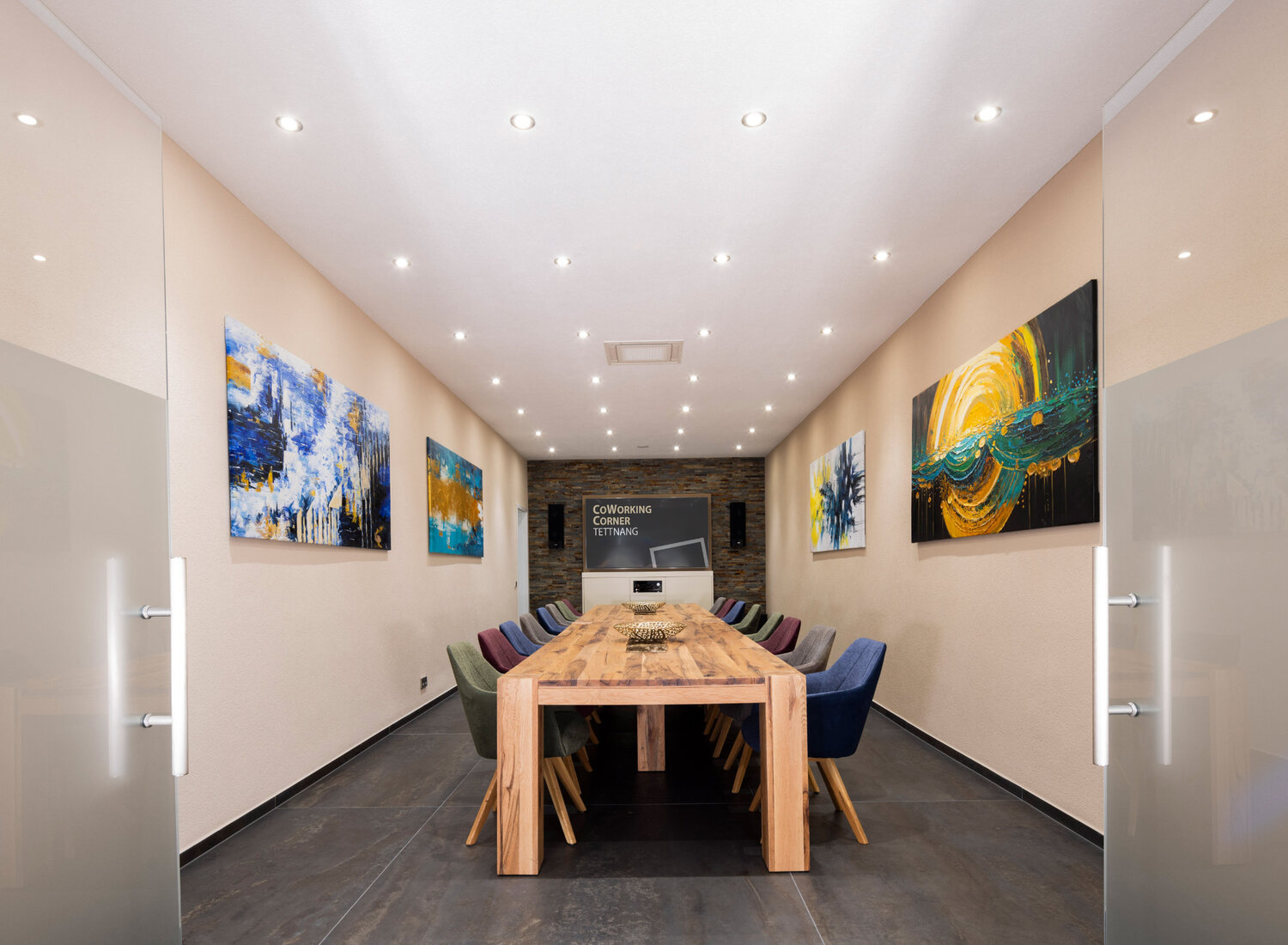 Der Meetingraum der CoWorking Corner Tettnang mit großen Holztisch und Bildschirm